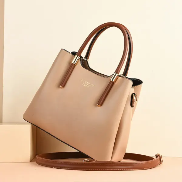 Tapered handbag angled on a display, with brown handles and a long strap
