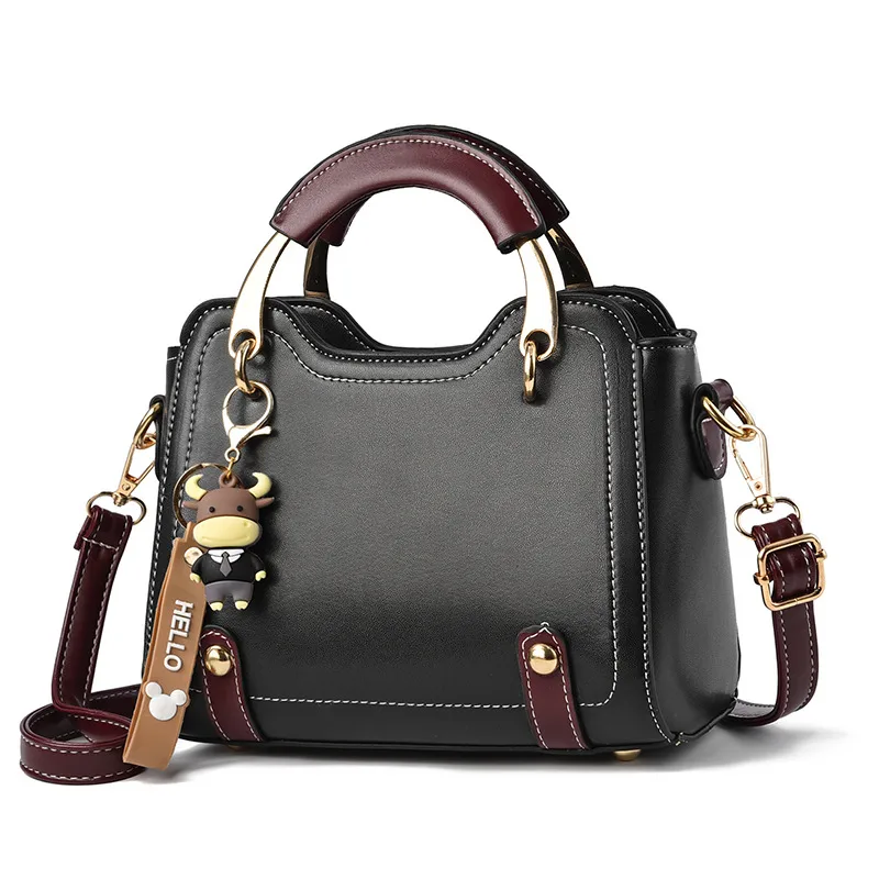 Close front view of a dark handbag showing curved gold-tone handle supports