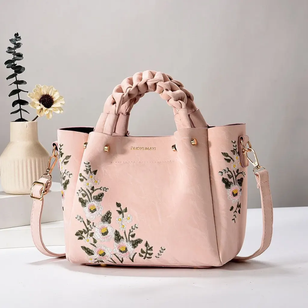 Blush Floral bag with braided handles, floral embroidery, and a long strap