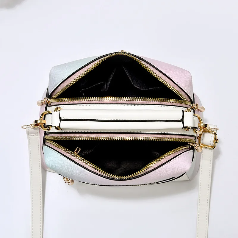 Top view of a white-trim pastel gradient handbag showing two visible zippered top compartments
