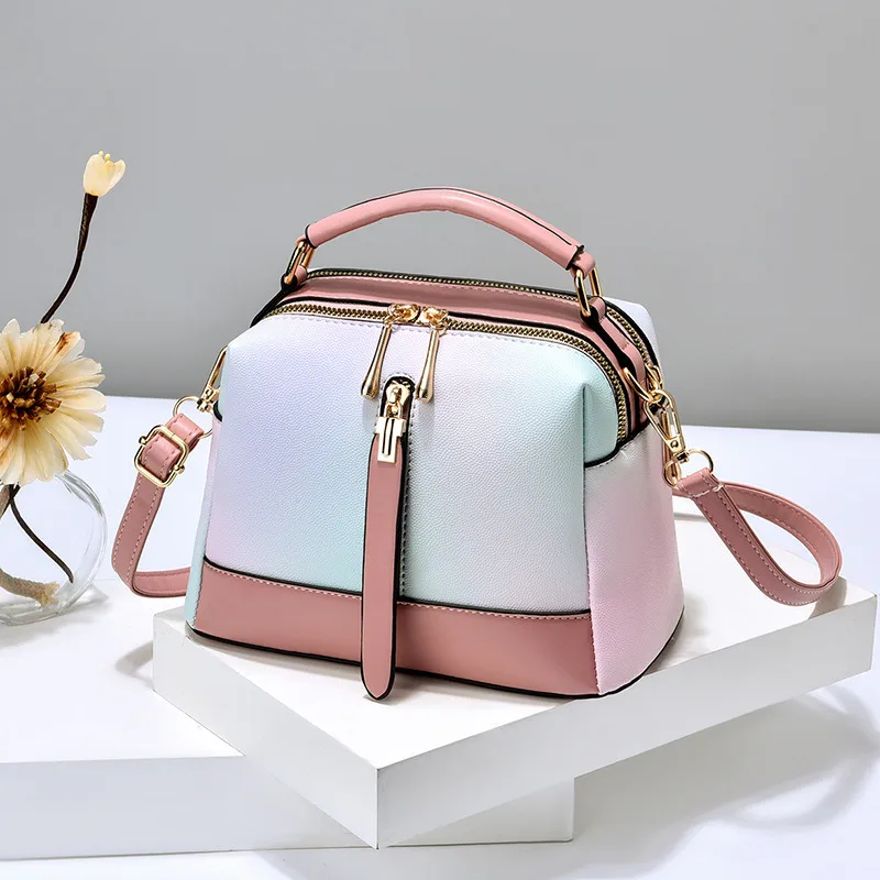 Pastel gradient handbag with pink trim, a top handle, and a long strap