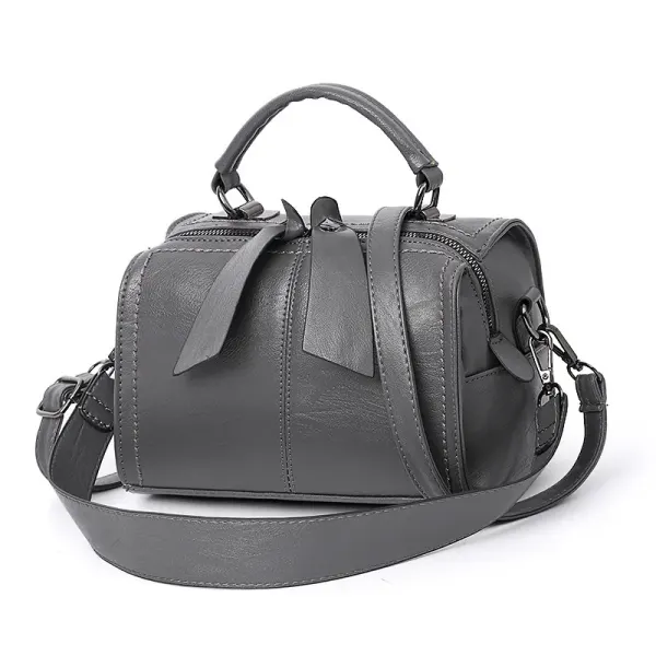 Charcoal rounded handbag with a top handle, long strap and two dangling zipper pulls