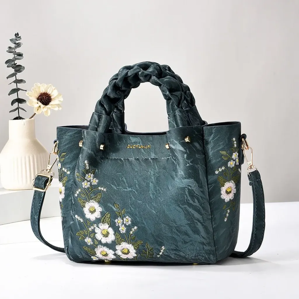 Teal Floral bag with braided handles, floral embroidery, and a long strap