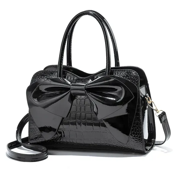 Jet Black croc-embossed handbag with a glossy front bow, two handles, and a long strap.